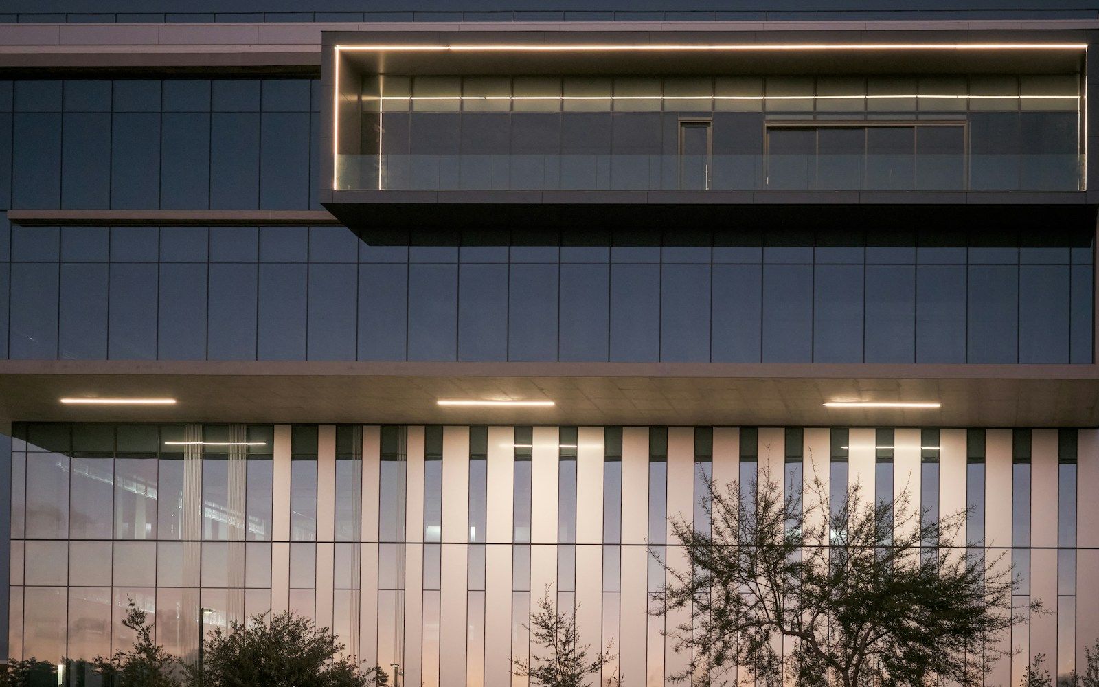 Occupied commercial office building illuminated at dusk.